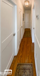 Finished hall with wooden floor, doors, wainscoting, and baseboards